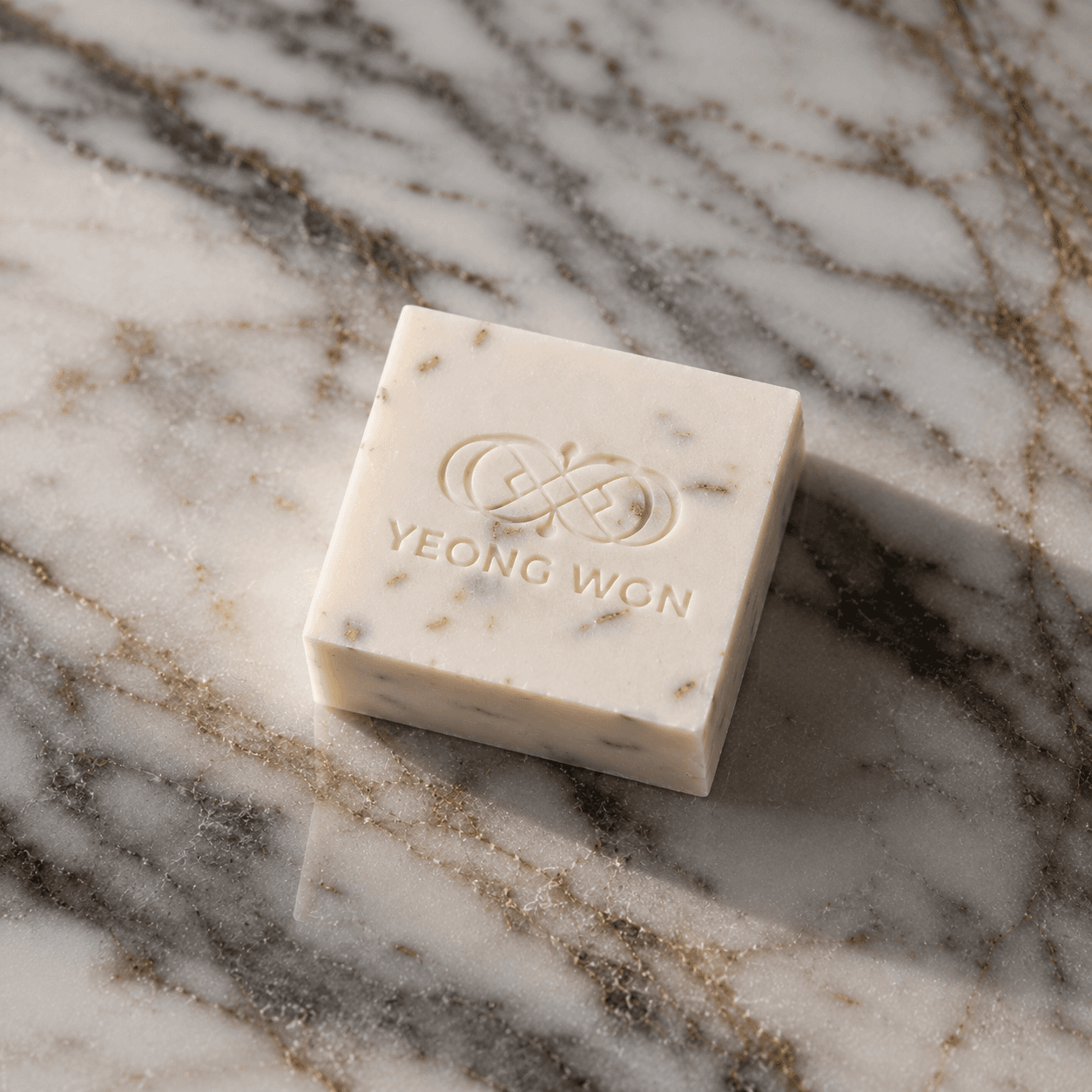 Cream Yeong Won soap bar embossed with the logo, seen from above on veined marble